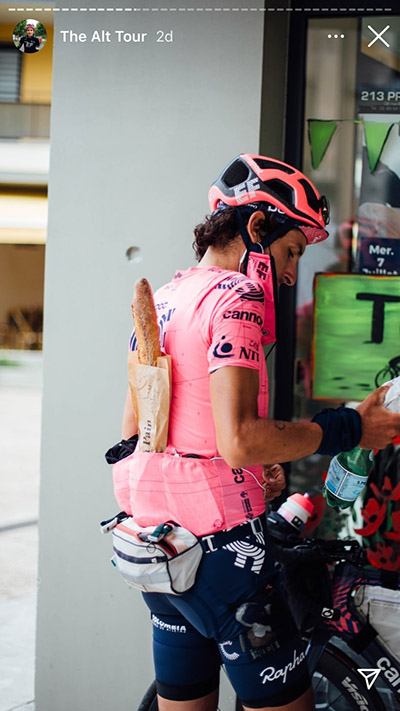 Mann in rosa Fahrradklamotten hat ein Baguette hinten im Trikot stecken